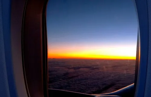 飞机窗口的照片，可以看到云朵和黄金时刻