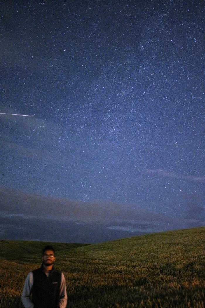 男人站在星空下的草地上