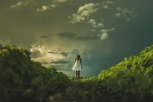 穿着无袖连衣裙的女人站在绿色的草地上