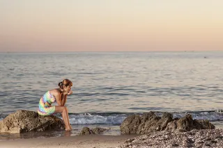 坐在海水附近岩石上的女人