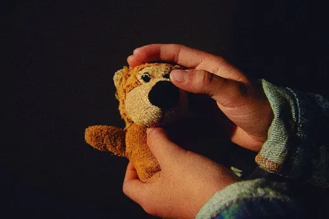 拿着棕色毛绒玩具的人