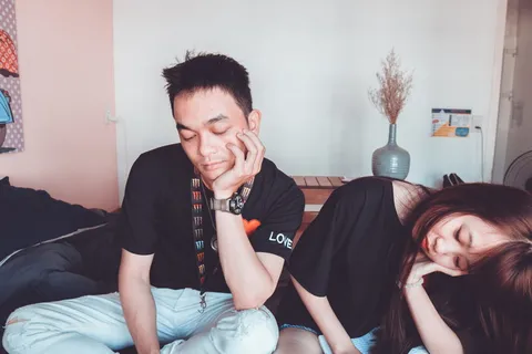 一名身穿黑色圆领衬衫的男子站在一名女子旁边