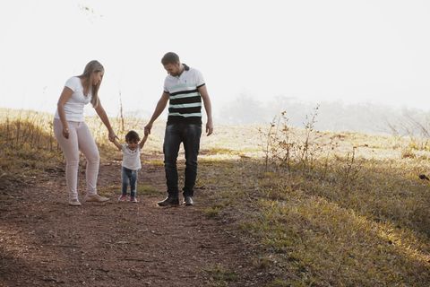 一对男女牵着女孩的手走在小路上