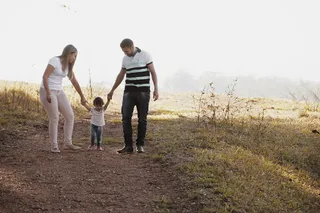 一对男女牵着女孩的手走在小路上