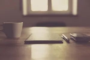 点击笔和白色杯子旁边的黑色封闭笔记本