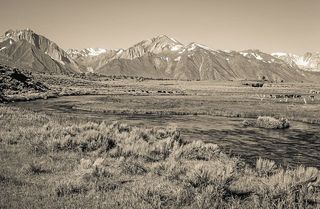 一条被绿草环绕的河流，背景是群山