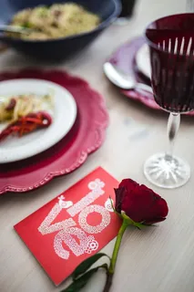 精美的晚餐，搭配海鲜意大利面、小龙虾和红酒，餐桌上装饰着玫瑰