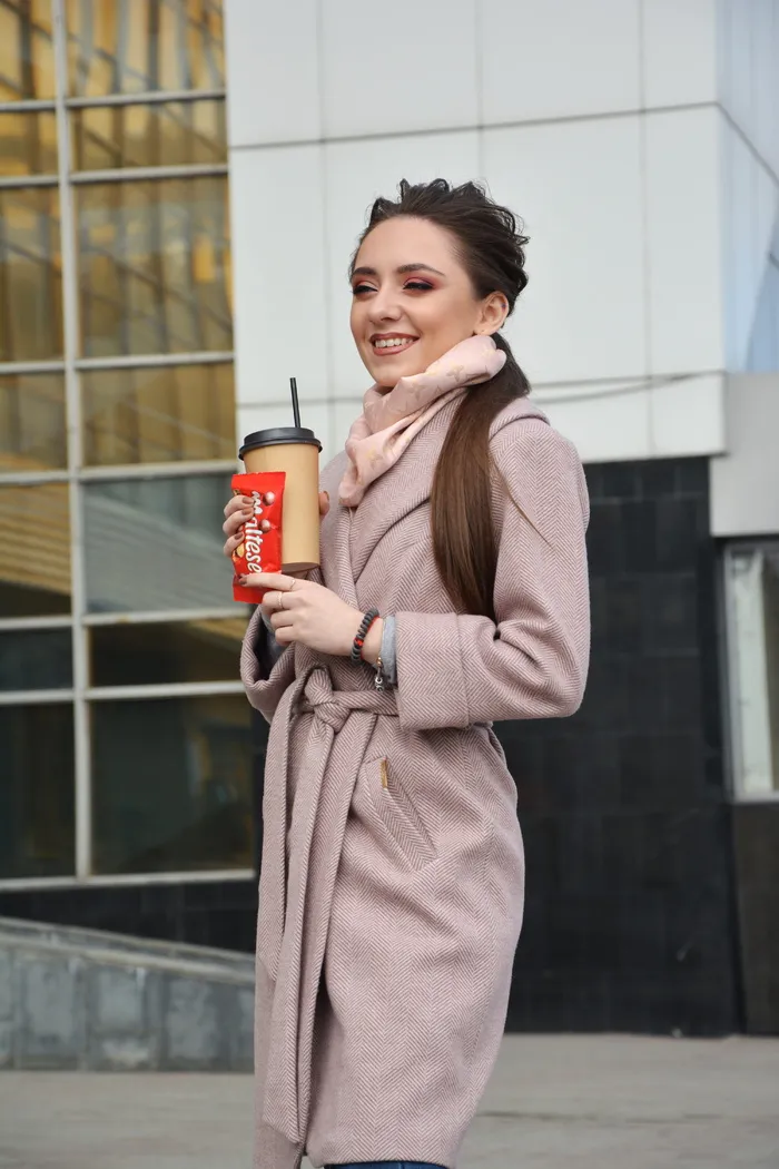 一个微笑的女人拿着塑料杯子和糖果包的照片