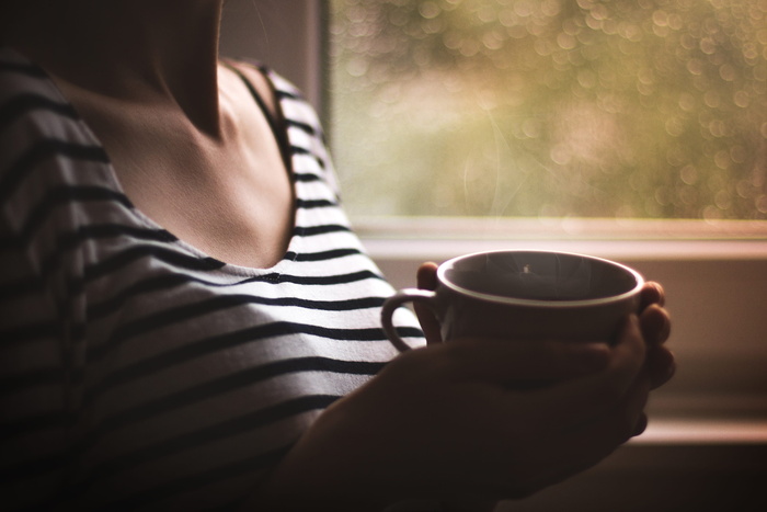 身穿黑白条纹上衣、手持白色陶瓷杯的女子