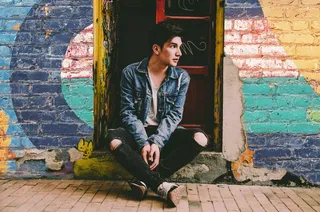 一个穿着蓝色牛仔夹克和黑色裤子的男人坐在门口