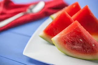 新鲜的西瓜片放在蓝色的桌面上，图像是用佳能单反相机拍摄的