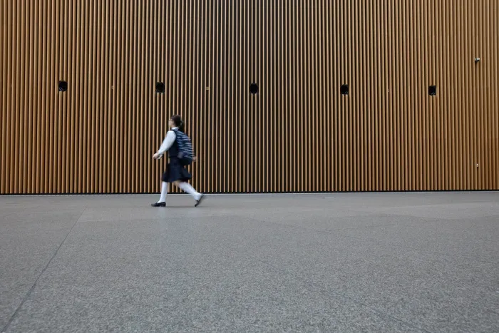 白天，穿着制服的女人在灰色水泥路面上行走