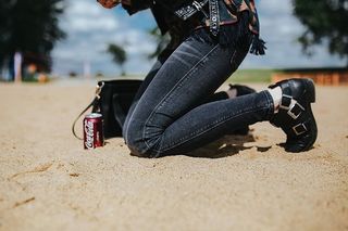 在海滩上穿着皮夹克和墨镜的年轻女子