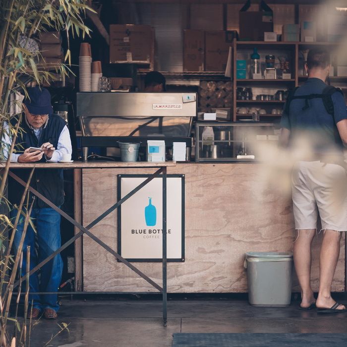 一名男子靠在咖啡店前的桌子上