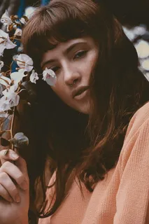 身穿橙色汗衫、手持白色花朵的女子 身穿橙色汗衫、手持白色花朵的女子