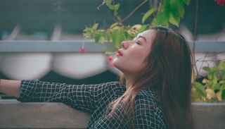 灰墙绿叶植物旁的女人