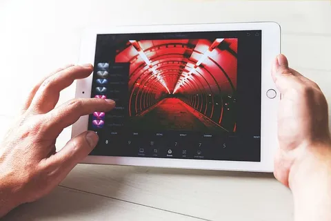 一名男子在iPad平板电脑的Lightroom photo应用程序中编辑照片