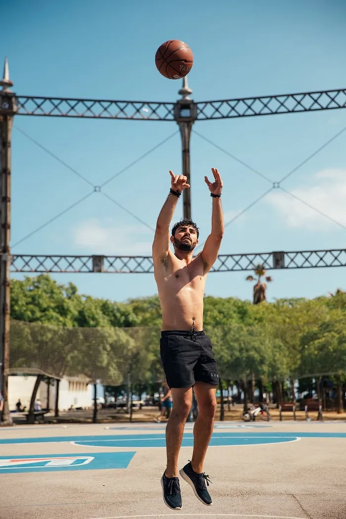 一个穿着黑色短裤的年轻人在户外篮球场上打篮球