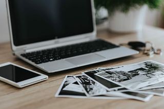 黑白照片，配有银色笔记本电脑、智能手机、车钥匙、铅笔和相机