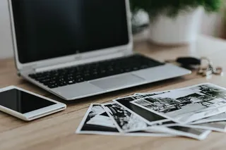 黑白照片，配有银色笔记本电脑、智能手机、车钥匙、铅笔和相机