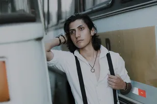 一名男子站在两辆公共汽车之间摆姿势的照片