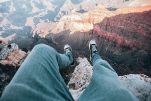 探险家双腿悬挂在峡谷边缘的俯视图