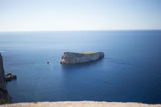 一个被蓝色海水环绕的岩石小岛，背景是地平线