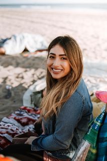 坐在展台顶部白色、红色和黑色条纹垫子上的女士