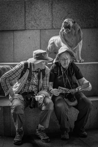 男人坐在女人旁边看地图的灰度照片