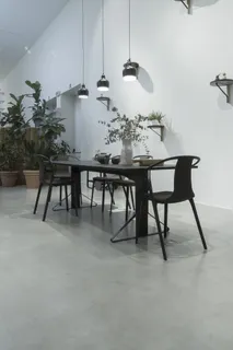 靠近白色墙壁的黑色木制桌子和金属椅子，桌子上方有三盏吊灯