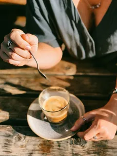 准备在透明玻璃杯子上搅拌棕色液体的人