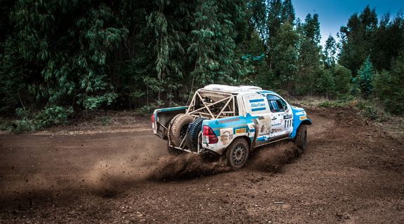 白色和蓝色皮卡车在弯道土路上漂移