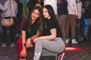 两个女人面带微笑，几乎坐在人群中