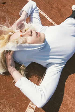 一位女士穿着套头连帽衫躺在铺着棕色地毯的地板上