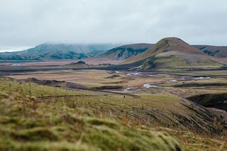 阴天，一个徒步旅行者在长满青苔的火山山上