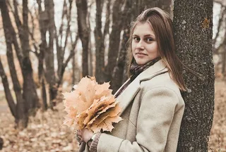 背倚在树上拿着树叶的女人