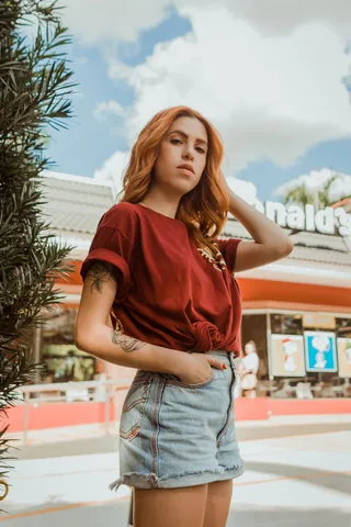 一名女子站在麦当劳前，右手伸进口袋，左手抓着头发