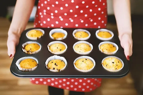 一位穿着漂亮的红色围裙的年轻女士刚刚烤了松饼