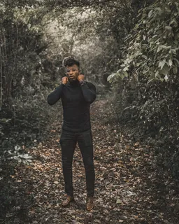 白天站着的男子穿着黑色高领毛衣和黑色修身裤,周围有树木 白天站着的男子穿着黑色高领毛衣和黑色修身裤,周围有树木