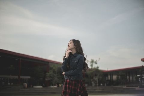 穿着蓝色牛仔夹克的站立女子触摸她的nck