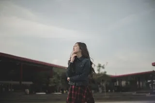 穿着蓝色牛仔夹克的站立女子触摸她的nck