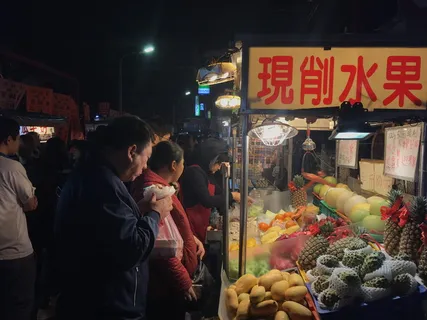 人们晚上站在水果车旁边