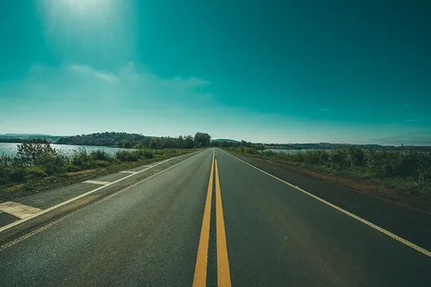 草地和水体之间道路的全景摄影 草地和水体之间道路的全景摄影