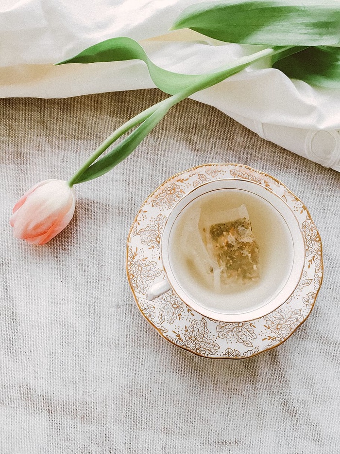 茶杯和茶托附近有粉红色花瓣的花