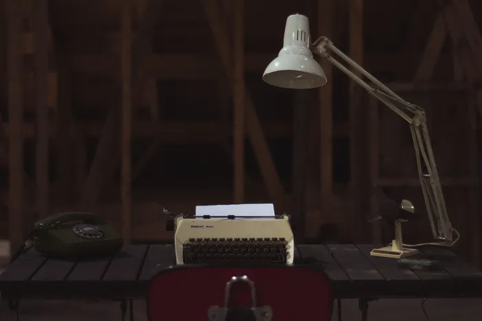 棕色桌子上电话旁边的黑白打字机
