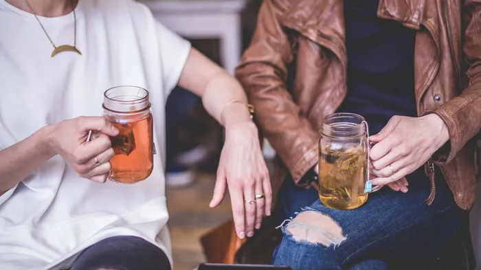 两个人坐着，拿着透明的玻璃梅森马克杯