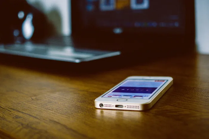 棕色木制书桌上的银色iPhone 5s