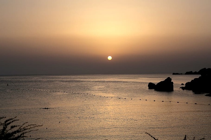 夕阳下的地平线上有波浪和岩石