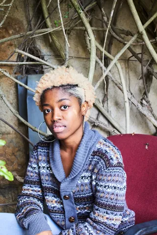 穿着蓝色、白色和棕色Fair isle纽扣开衫的女士坐在红色椅子上