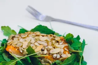 绿叶覆盖着芝麻籽的肉，旁边有叉子